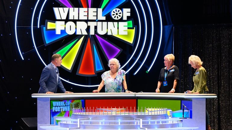 Mark L. Walberg, left, serves as host of “Wheel of...