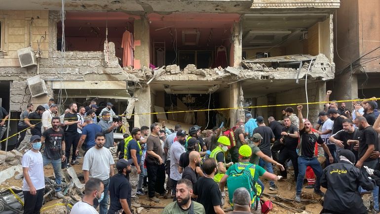 People gather near a damaged building at the scene of...