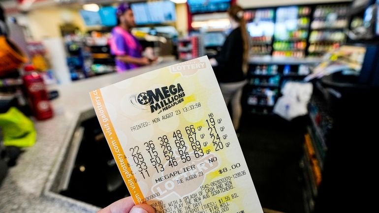 A Mega Millions ticket is seen as a person makes...