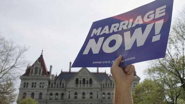 Andrew Chapin of New York holds a sign during a...