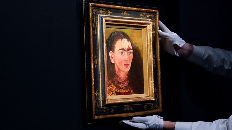 An art handler adjusts Frida Kahlo's “Diego and I” on...