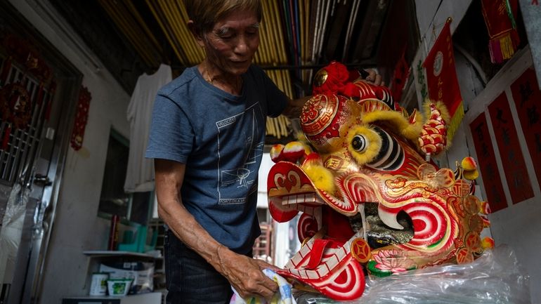 Villager Lo Yuet-ping cleans the head prop that's used in...