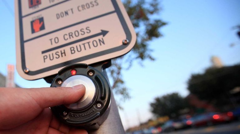 A pedestrian trying to cross Hempstead Turnpike pushes a button...