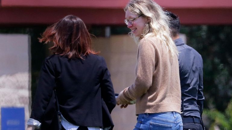 Disgraced Theranos CEO Elizabeth Holmes, center, is escorted by prison...