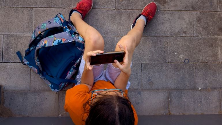 A 11-year-old boy plays with his father's phone outside school...