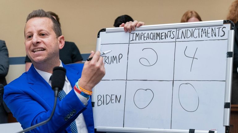 Rep. Jared Moskowitz, D-Fla., holds up a whiteboard he wrote...