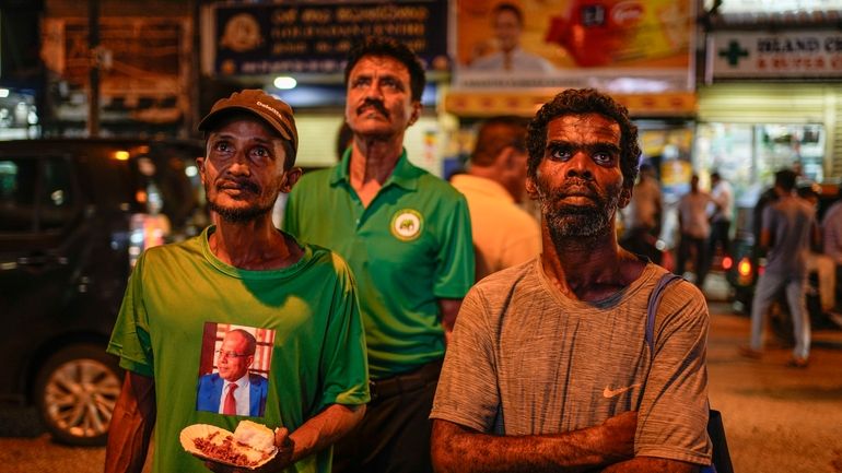 Supporters of Sri Lanka's President Ranil Wickremesinghe watch a televised...