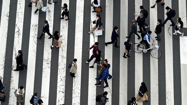 People walk along a pedestrian crossing at Ginza shopping street...