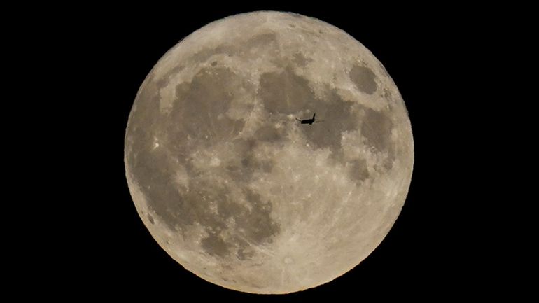 A plane passes in front of the moon in a...