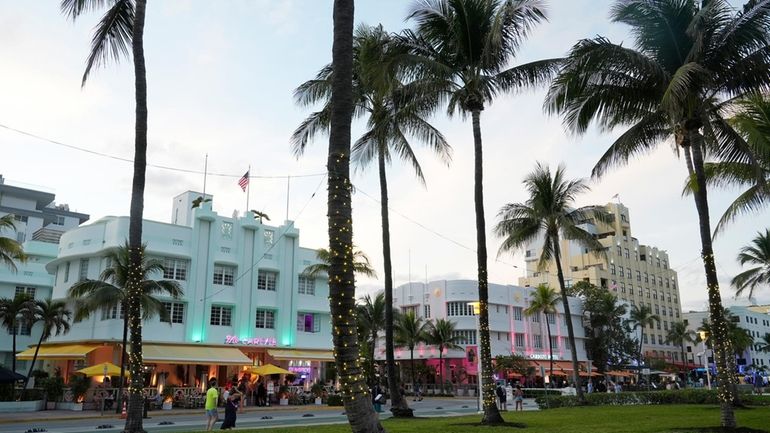 Pedestrians walk along Ocean Drive with its beautiful Art Deco...