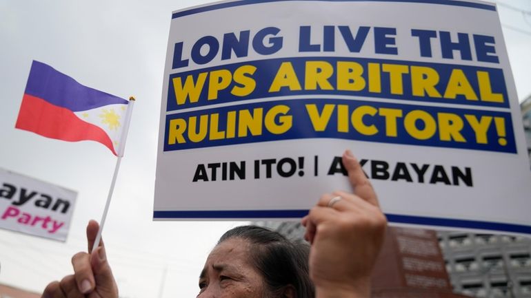 A demonstrator holds a slogan and a small Philippine flag...