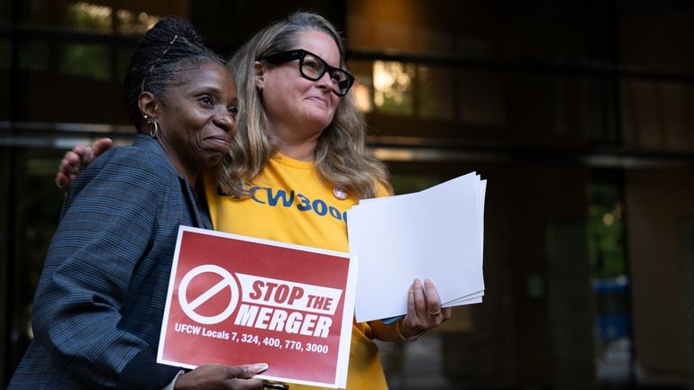 Faye Guenther, president of local UFCW 3000, hugs Carol McMillian,...