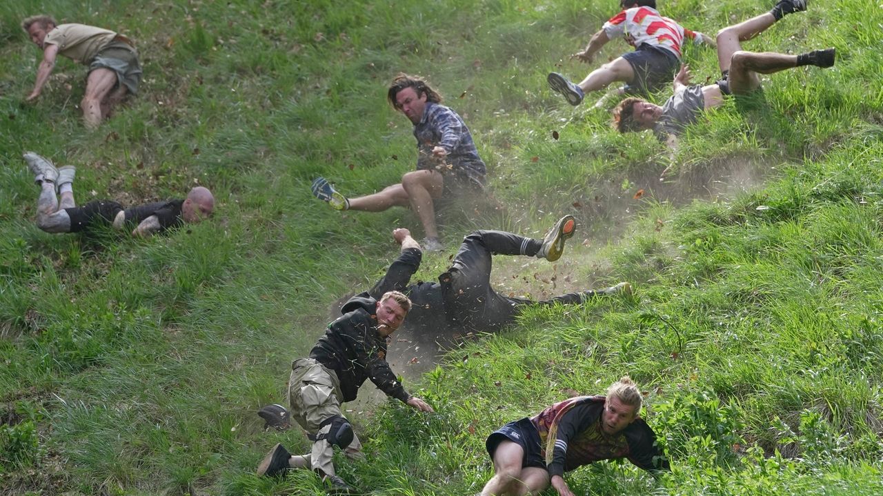 Rolling thunder Contestants chase cheese wheel down a hill in chaotic