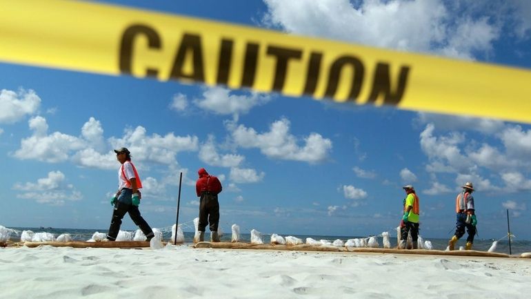 Workers place absorbent material along the water line Sunday to...