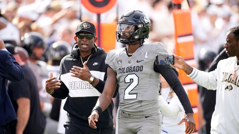 Colorado head coach Deion Sanders, left, talks with his son,...