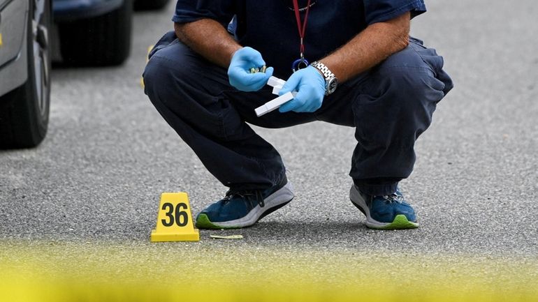 A crime lab investigator recovers a shell casing from scene of...