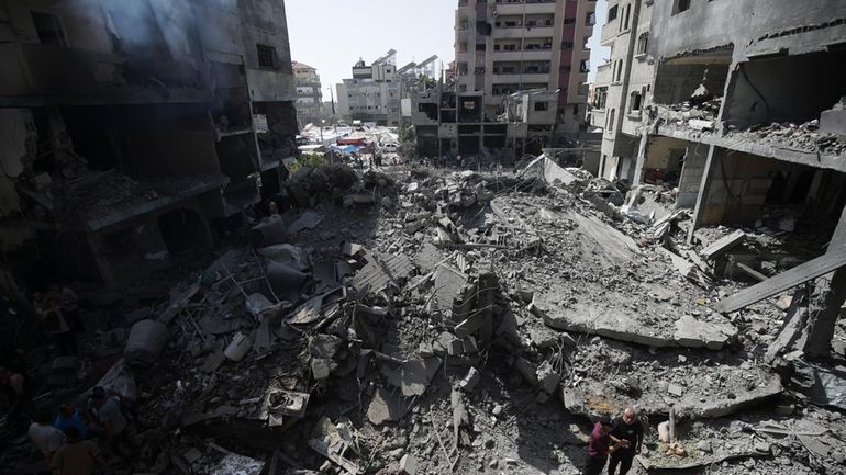 Palestinians look at the aftermath of the Israeli bombing in...