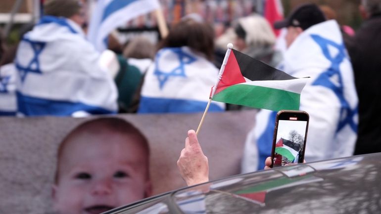 A person waves a palestinian flag while passing a pro-israel...