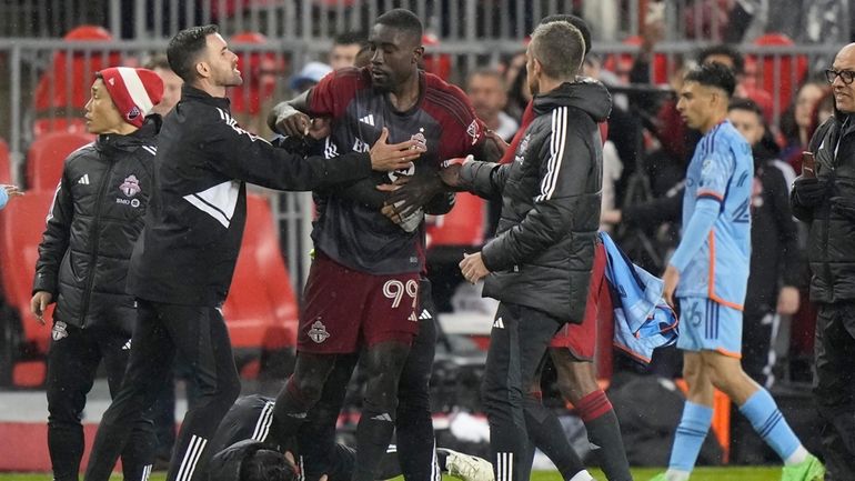 Toronto FC forward Prince Osei Owusu (99) is restrained by...