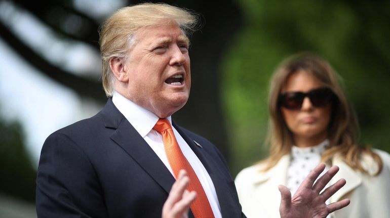 President Donald Trump answers questions, with first lady Melania Trump...