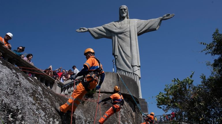 Trash collectors rappel down Corcovado Mountain to remove garbage dumped...