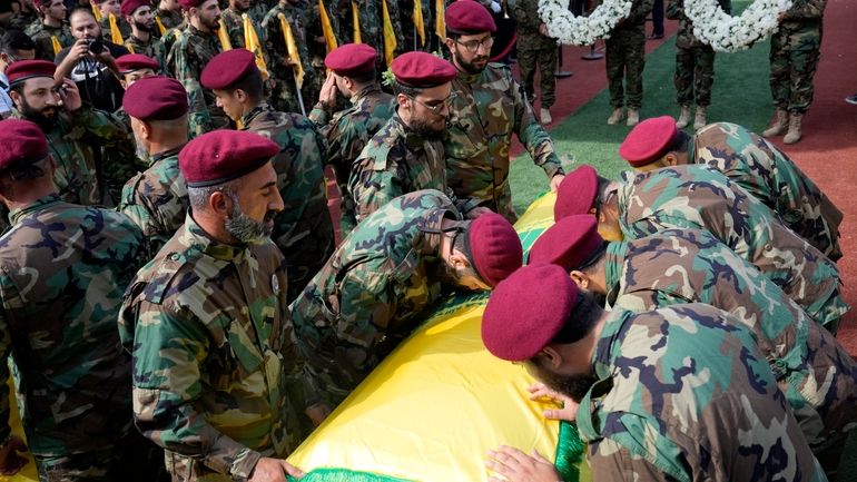 Hezbollah members mourn over the coffins of two of their...