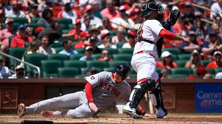 Boston Red Sox's Garrett Cooper, left, slides safely into home...