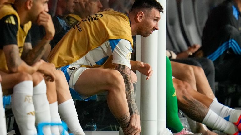 Argentina's Lionel Messi touches his ankle sitting at the bench...