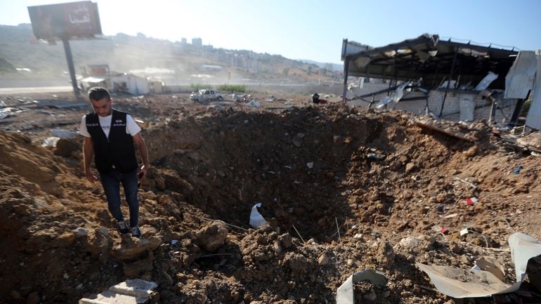 A Lebanese police intelligence stands near a crater at the...