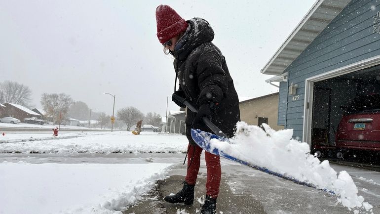 Laura Davenport shovels snow, Thursday, Oct. 26, 2023, in Bismarck,...