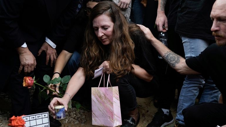 Ricarda Louk places a candle on the grave of her...