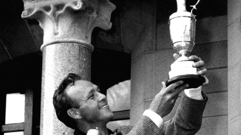 British Open champion Arnold Palmer poses with his trophy held...