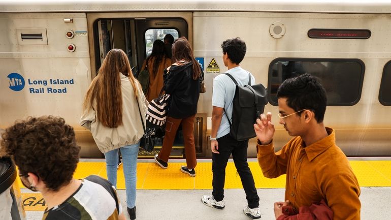 Commuters board a train at the Hicksville LIRR station this...