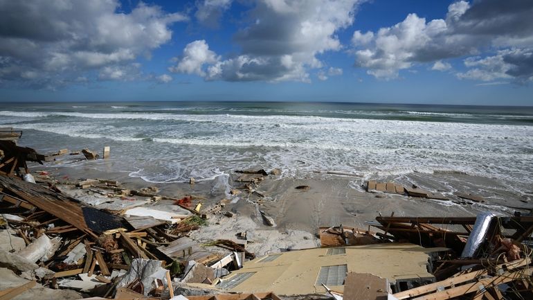 A piece of wall is seen amid the wreckage of...