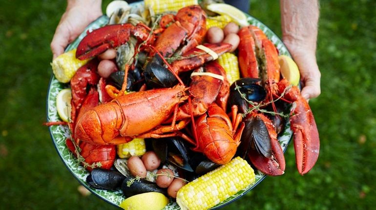 A plate of lobsters, mussels, clams, corn and potatoes create...