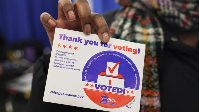 A voter shows her "I voted" sticker after casting her...