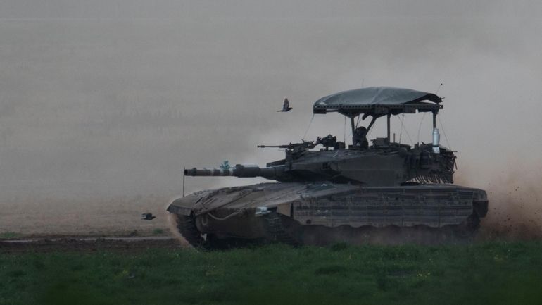 Israeli soldier moves on the top of a tank near...