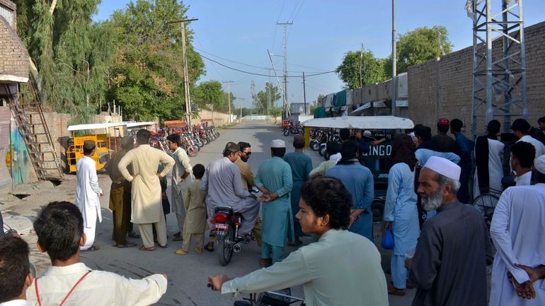 Local residents gather at a barricaded road leading to a...