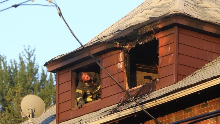 A firefighter looks at fire damage in a house on...