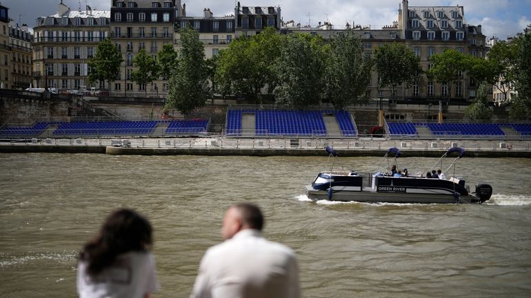 People sit along the Seine River with stands installed on...