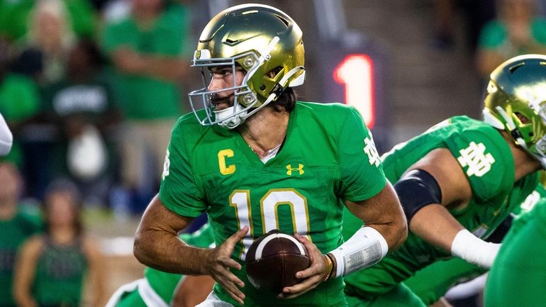 Notre Dame quarterback Sam Hartman looks to hand the ball...