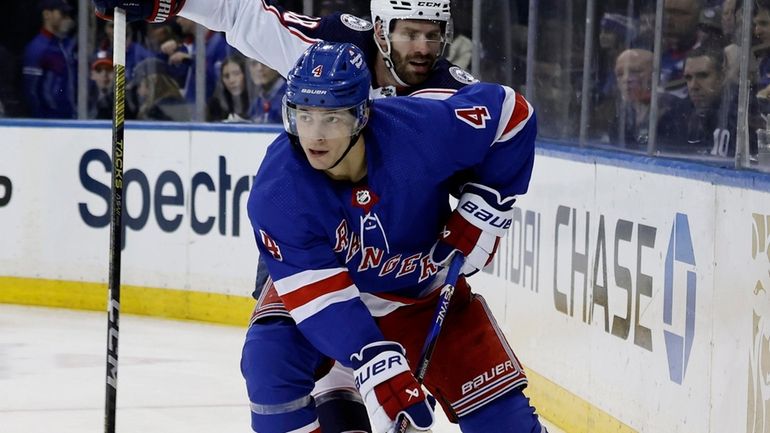 Braden Schneider of the New York Rangers plays the puck...