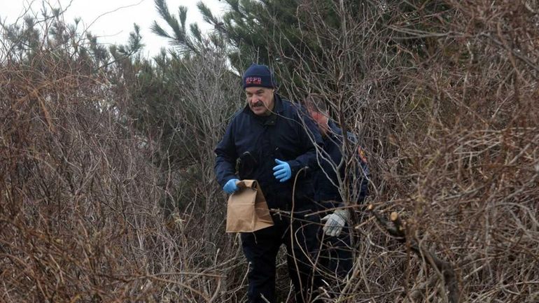 Nassau County police crime scene investigators remove a bag of...