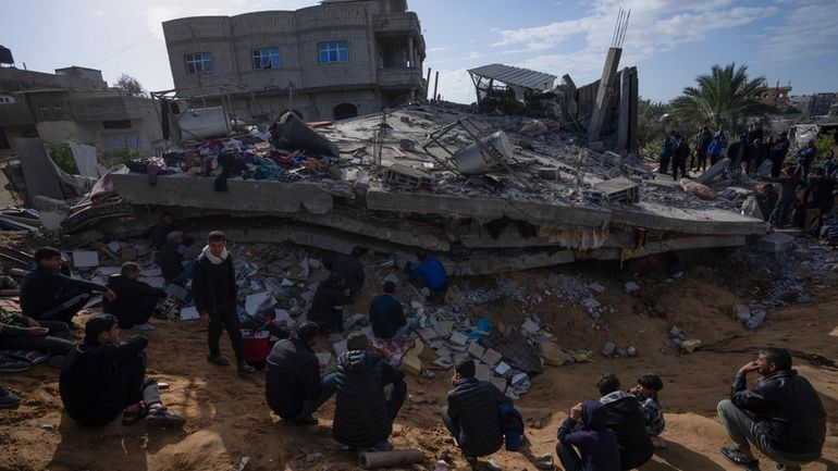 Palestinians search for bodies and survivors in the rubble of...