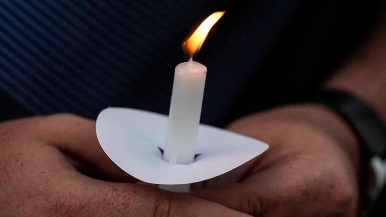 Mark Gorman holds a candle during a candlelight vigil for...