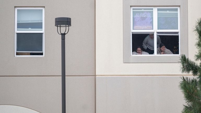 Students look outside their dorm window in the Village at...