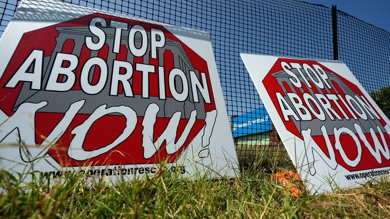 Anti-abortion signs lean agains a fence outside a recently opened...