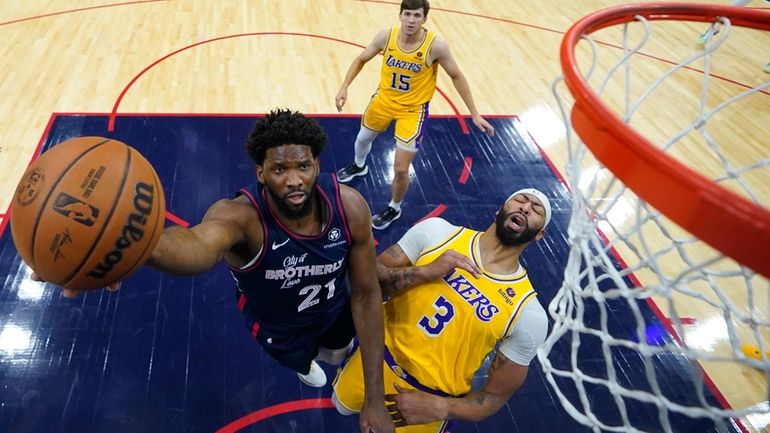 Philadelphia 76ers' Joel Embiid, left, goes up for a shot...