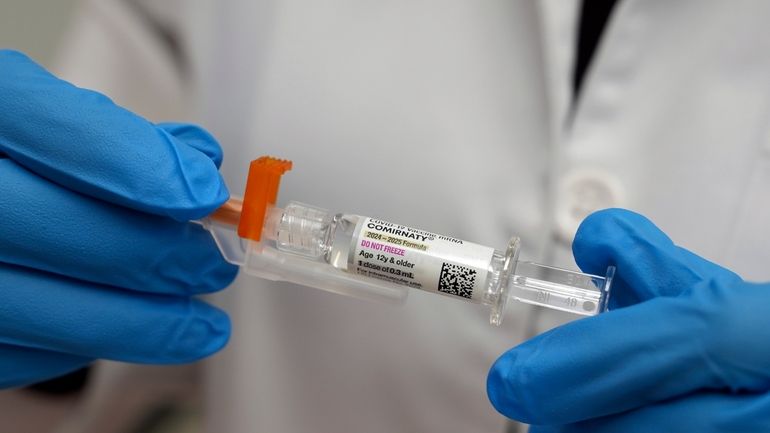 A pharmacist holds a COVID-19 vaccine at a pharmacy in...