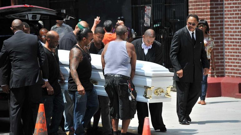 Family and friends move the casket of Eric Garner into...